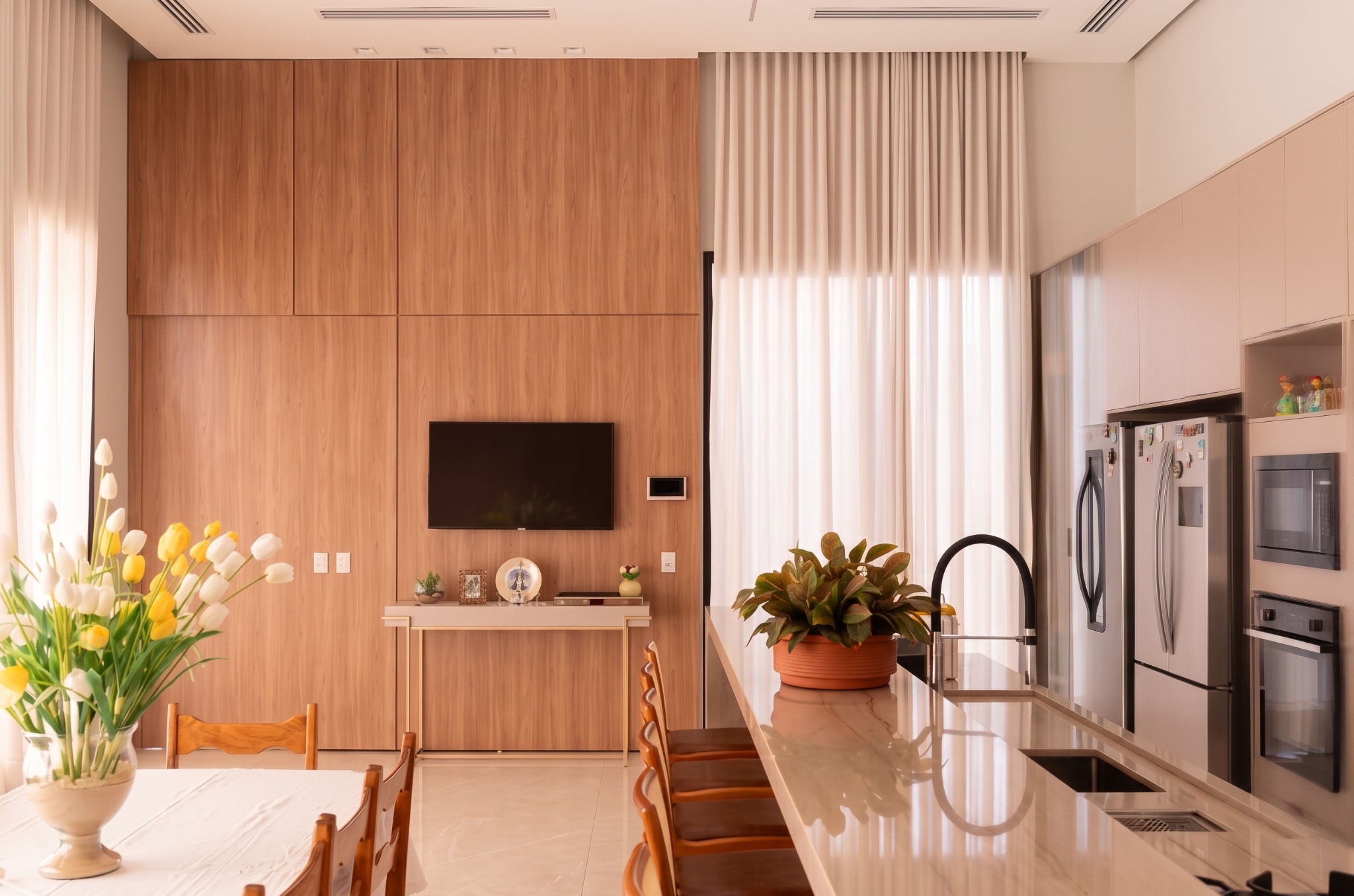Cozinha integrada com marcenaria em madeira e painel para televisão