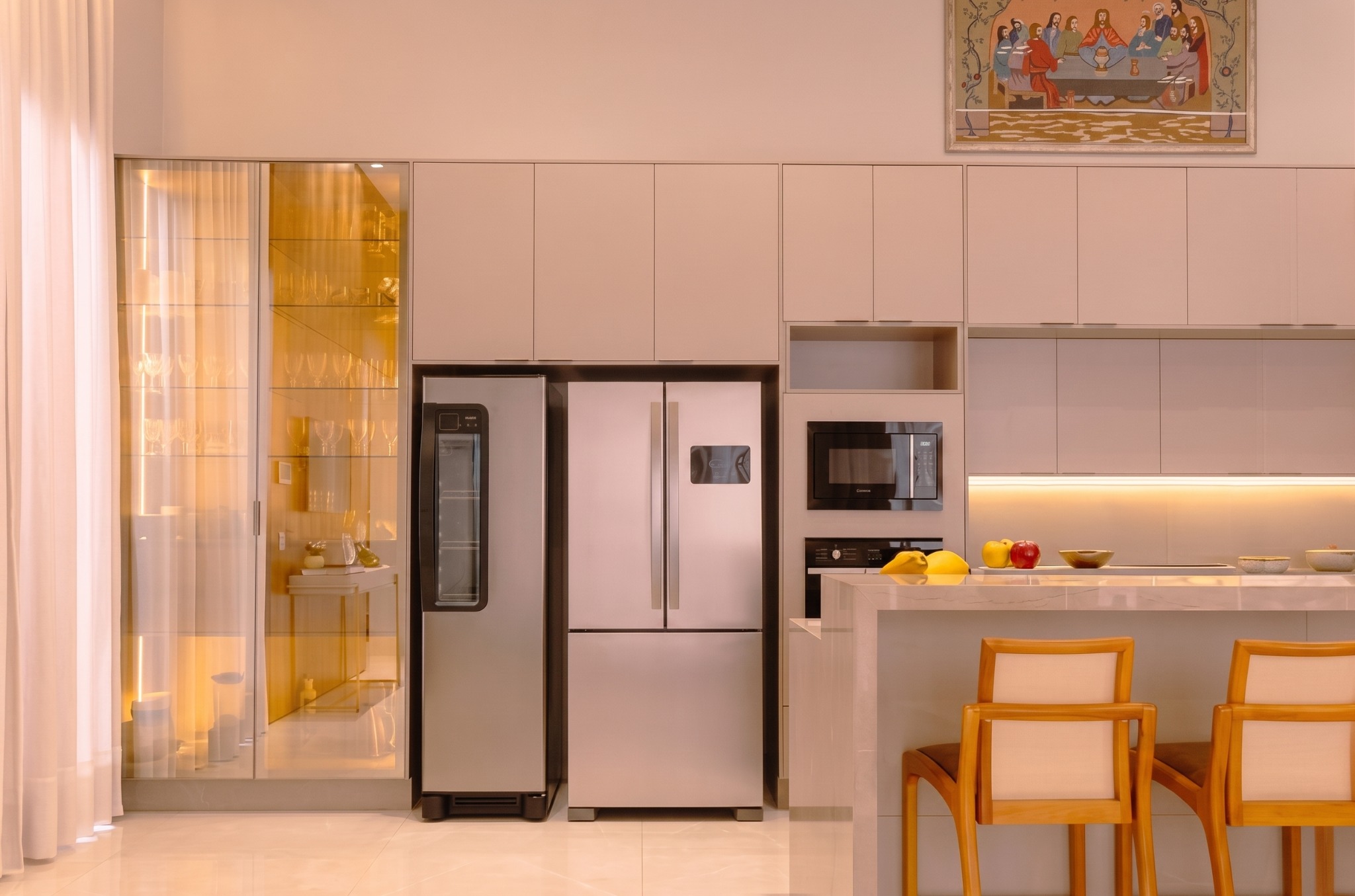 Cozinha clara com ilha, torre de eletros e iluminação quente